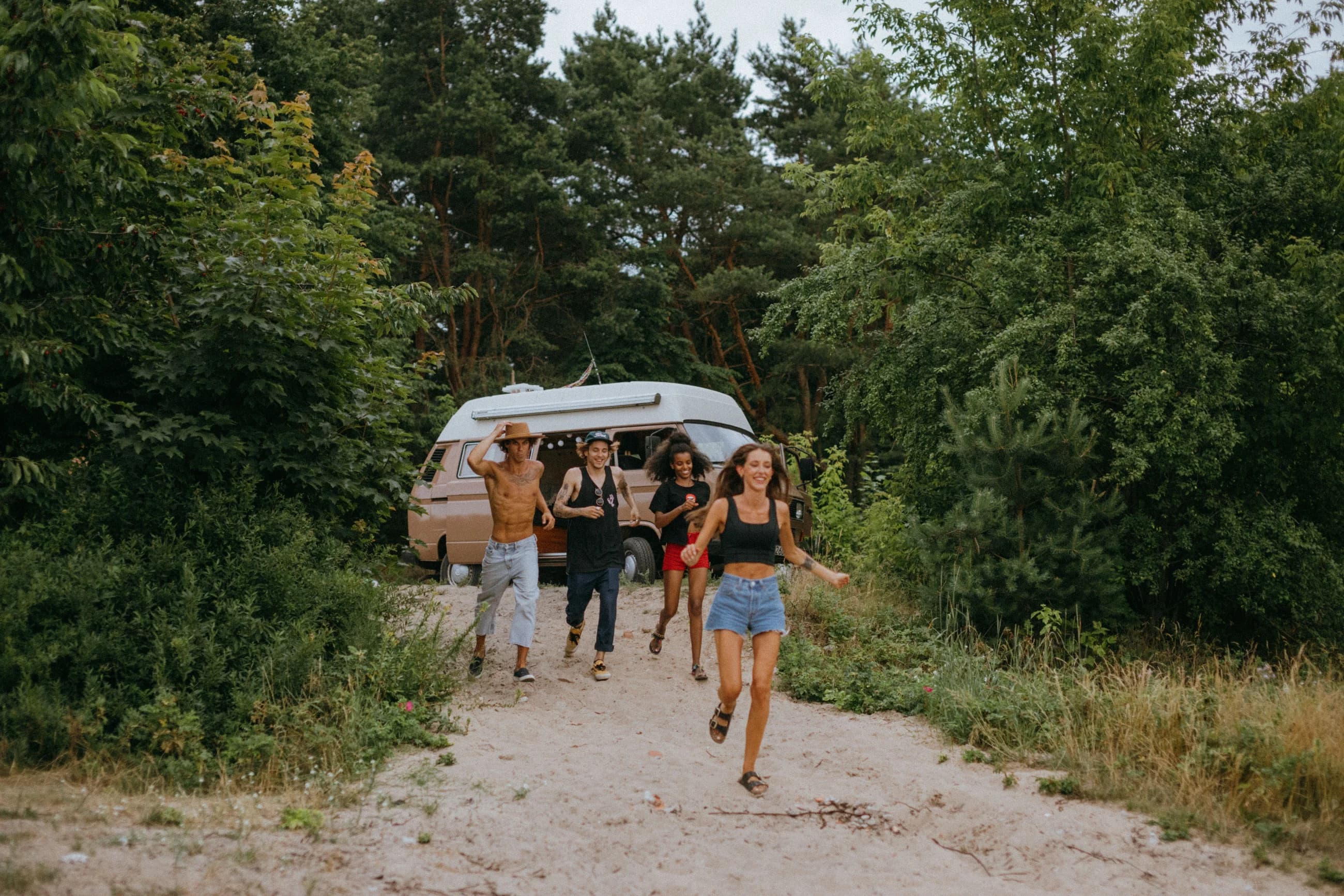 Freunde kommen lachend aus dem Wald auf den Weg zu