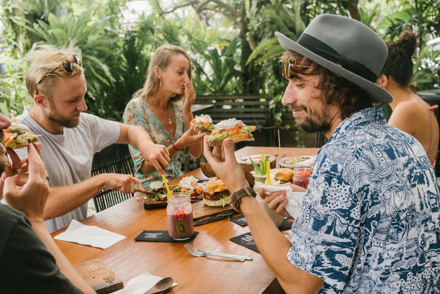 Freunde sitzen draußen zusammen, essen und lachen